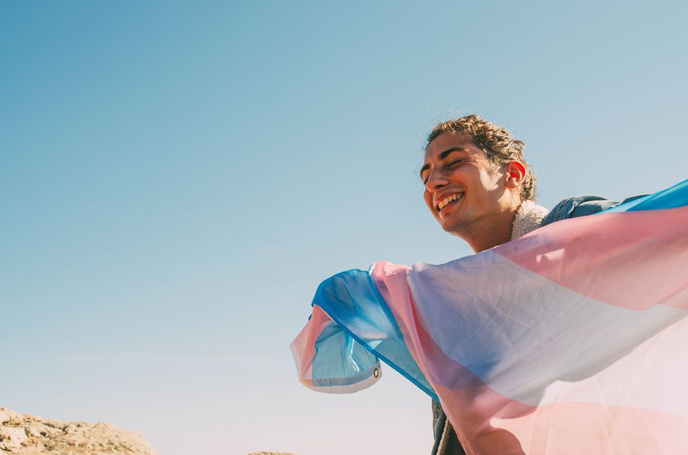 une personne tenant un drapeau trans