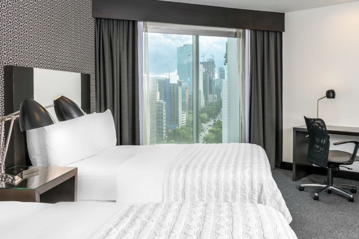 Hôtel Gay Friendly Le Méridien Mexico.  Lit avec fenêtre et ville en arrière-plan.