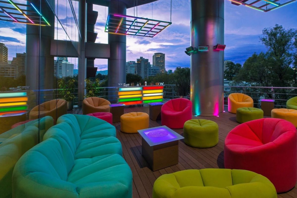 Hôtel gay-friendly W Mexico.  Chaises et lumières de couleur arc-en-ciel avec coucher de soleil en arrière-plan.