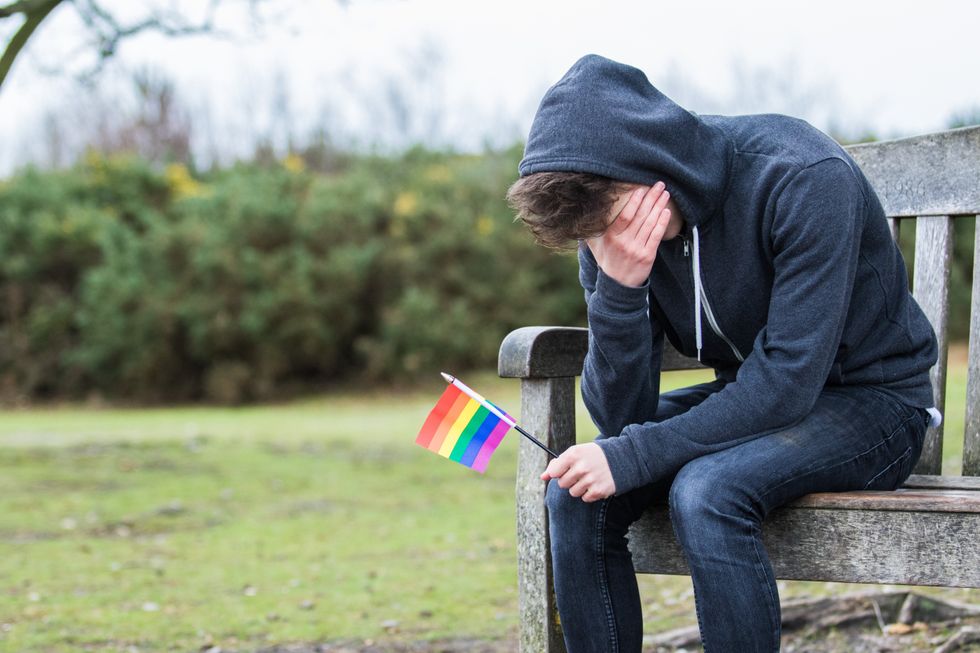 homme gay tenant un drapeau arc-en-ciel étant triste