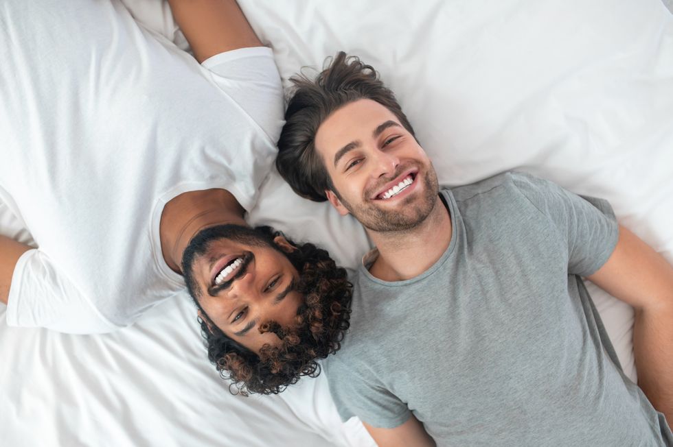 deux hommes souriants au lit