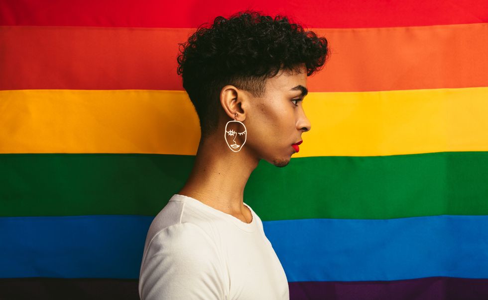 personne queer posant devant un drapeau de la fierté
