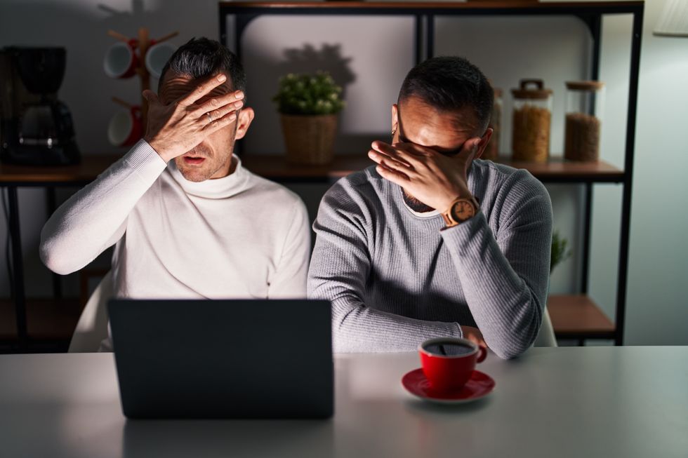 deux hommes se couvrant les yeux devant un ordinateur