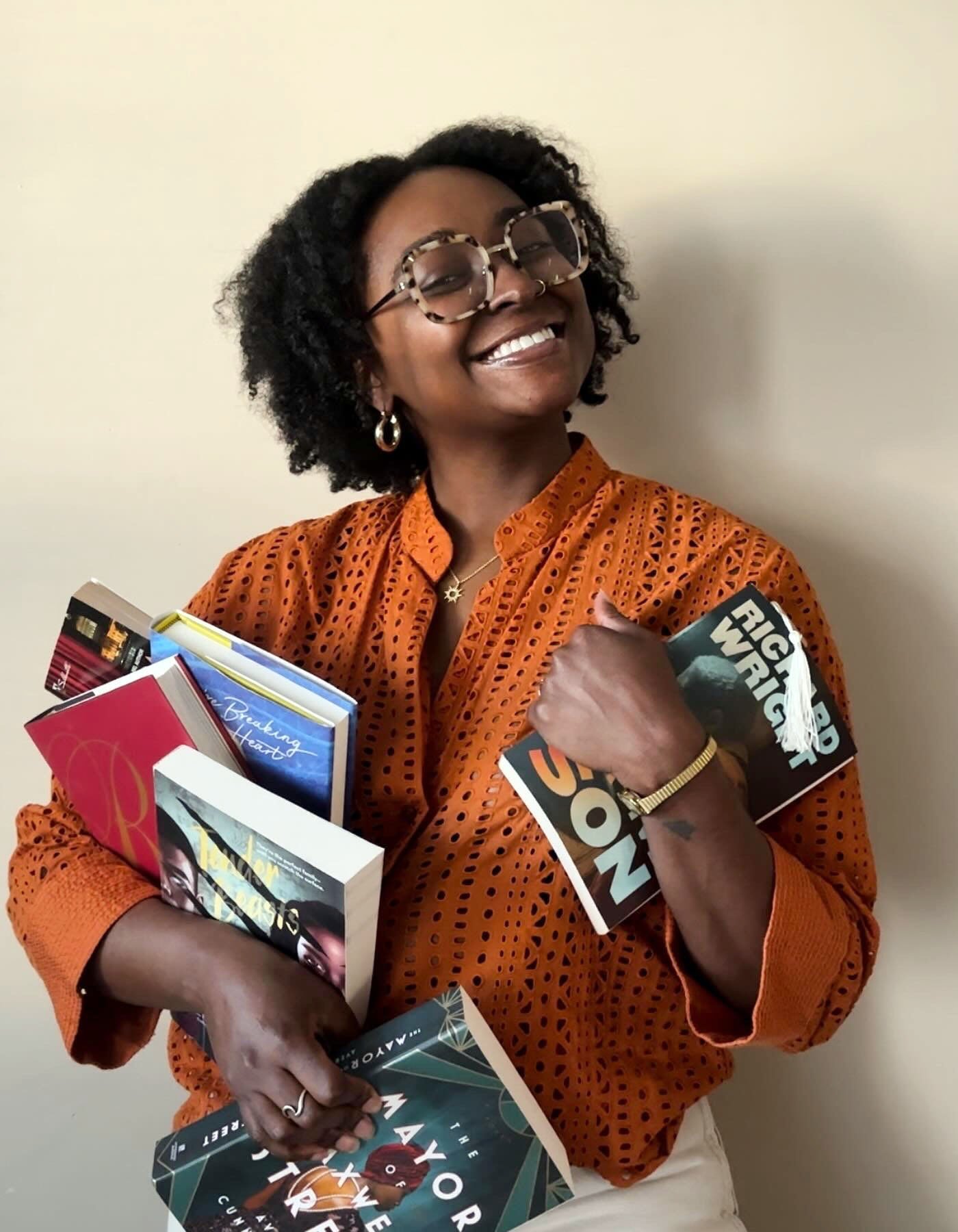 Portrait de Dawnshaeé Reid tenant de nombreux livres différents tout en souriant.